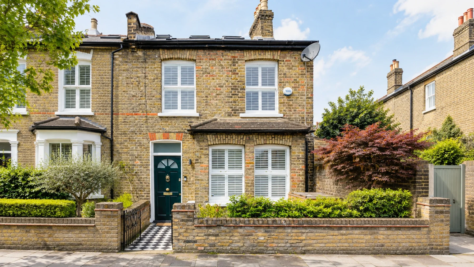 End-of-terrace London stock brick house with a black flat-roof dormer loft conversion above