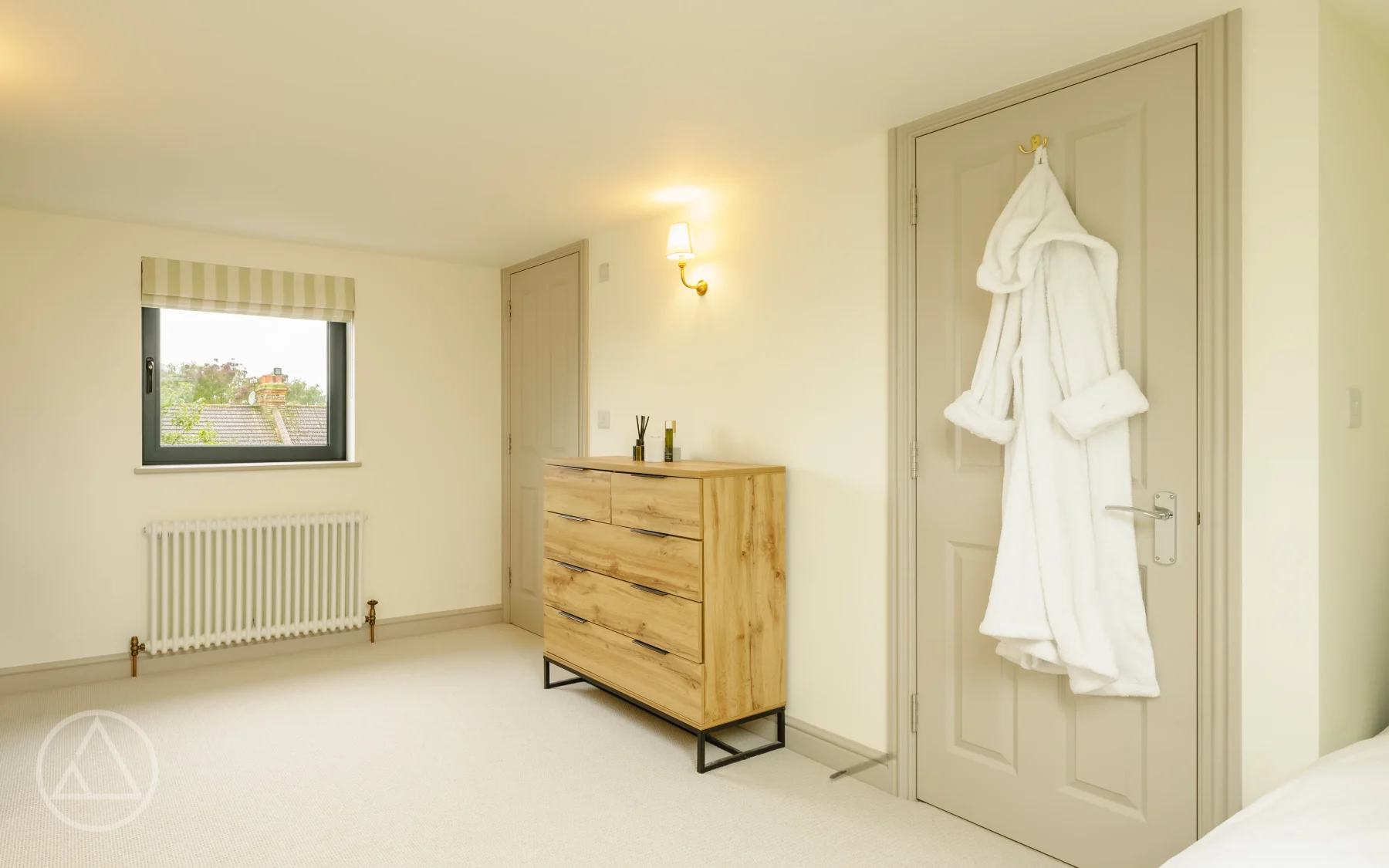 Loft bedroom on Carlton Park with an oak chest of drawers, striped roman blind and a rooftop view