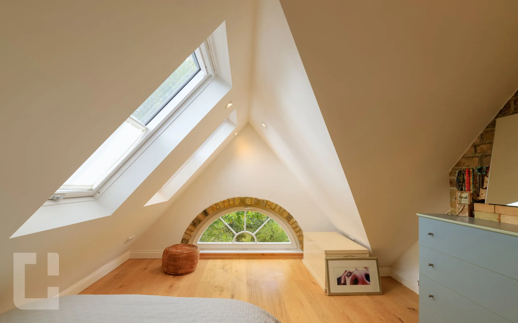 Loft bedroom with an original arched brick gable window and two Velux rooflights above