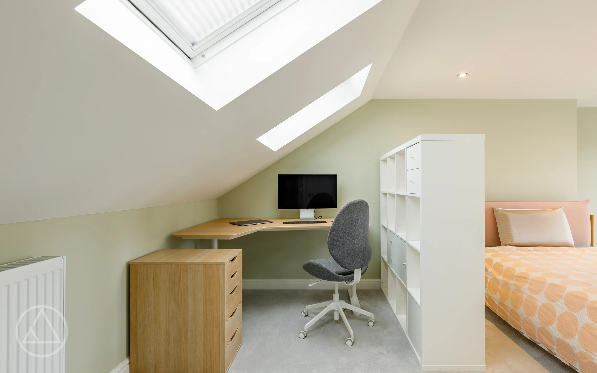 Loft bedroom with a corner desk and two rooflights, divided from the bed by cube shelving