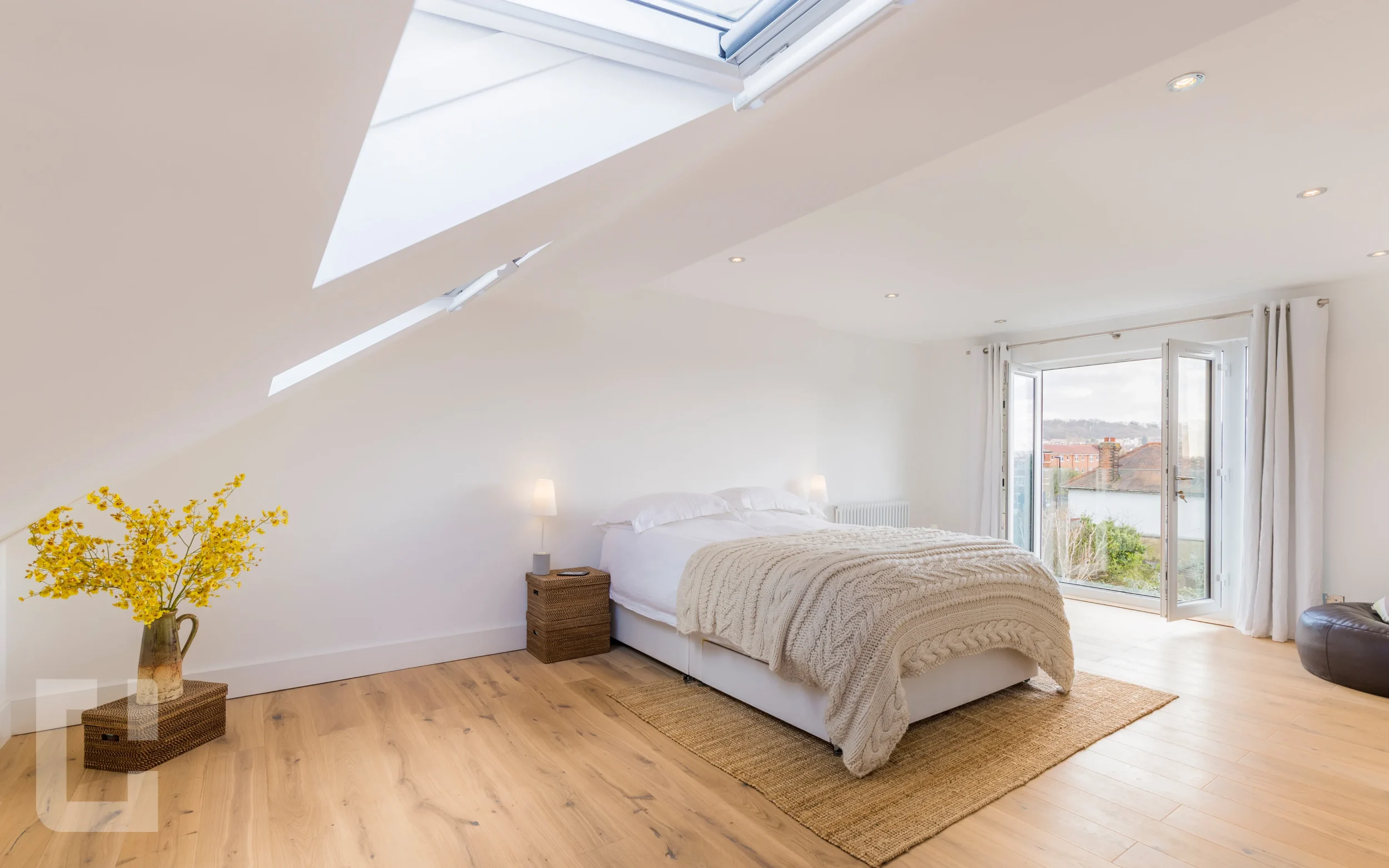 Loft bedroom with French doors onto a glass Juliet balcony and large rooflights above