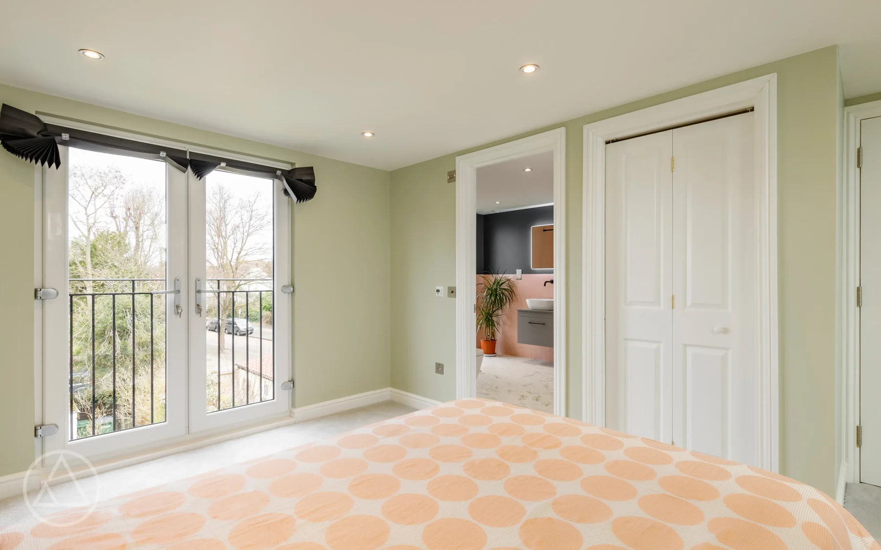 Loft bedroom with French doors to a Juliet balcony, fitted wardrobes and an en-suite beyond