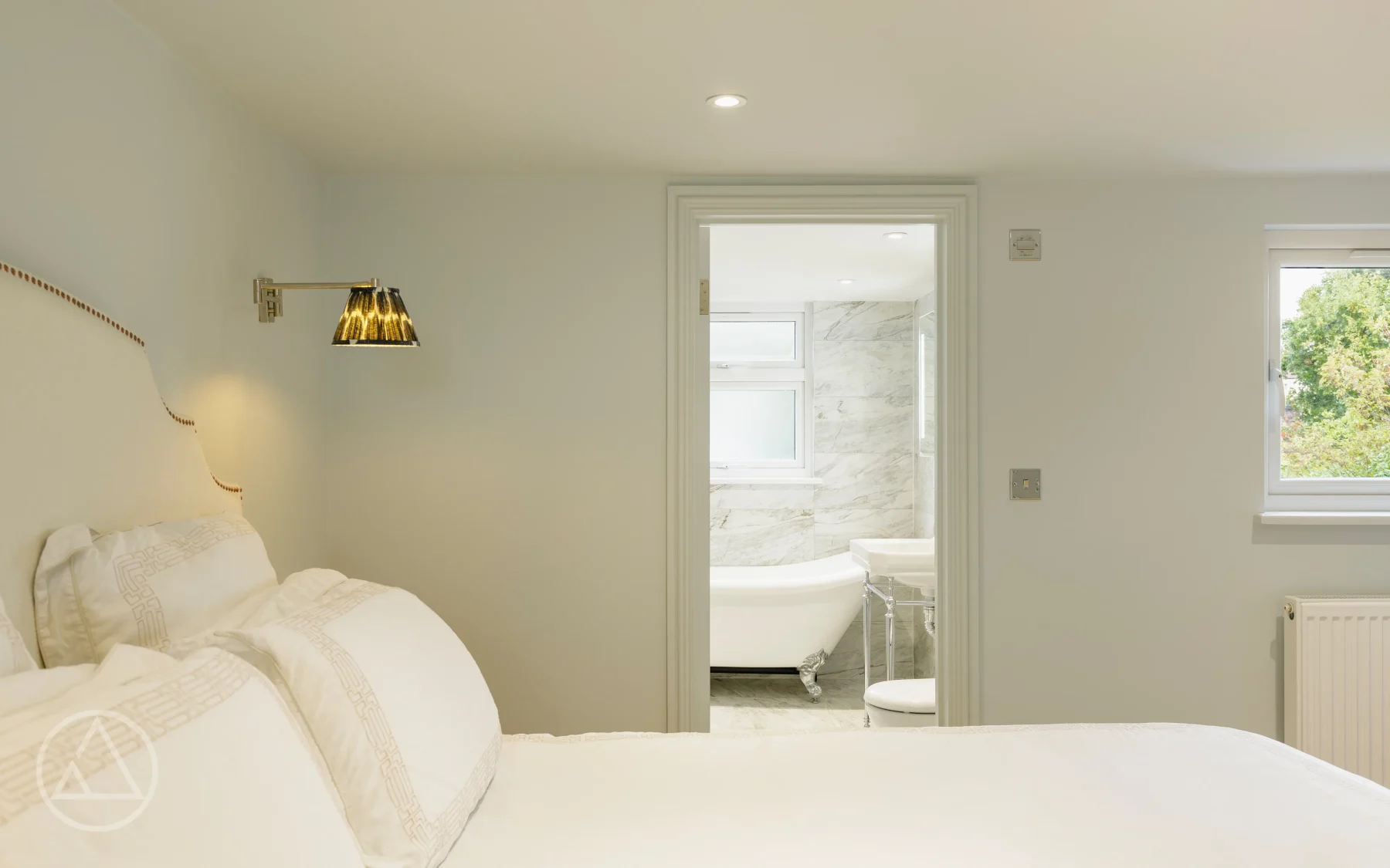 Loft bedroom on Blagdon Road looking through an open doorway to a marble en-suite with a roll-top bath