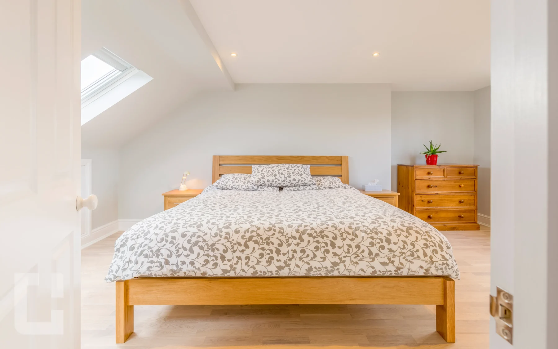 Loft bedroom in Eltham with a solid oak bed, rooflight and pale wood flooring