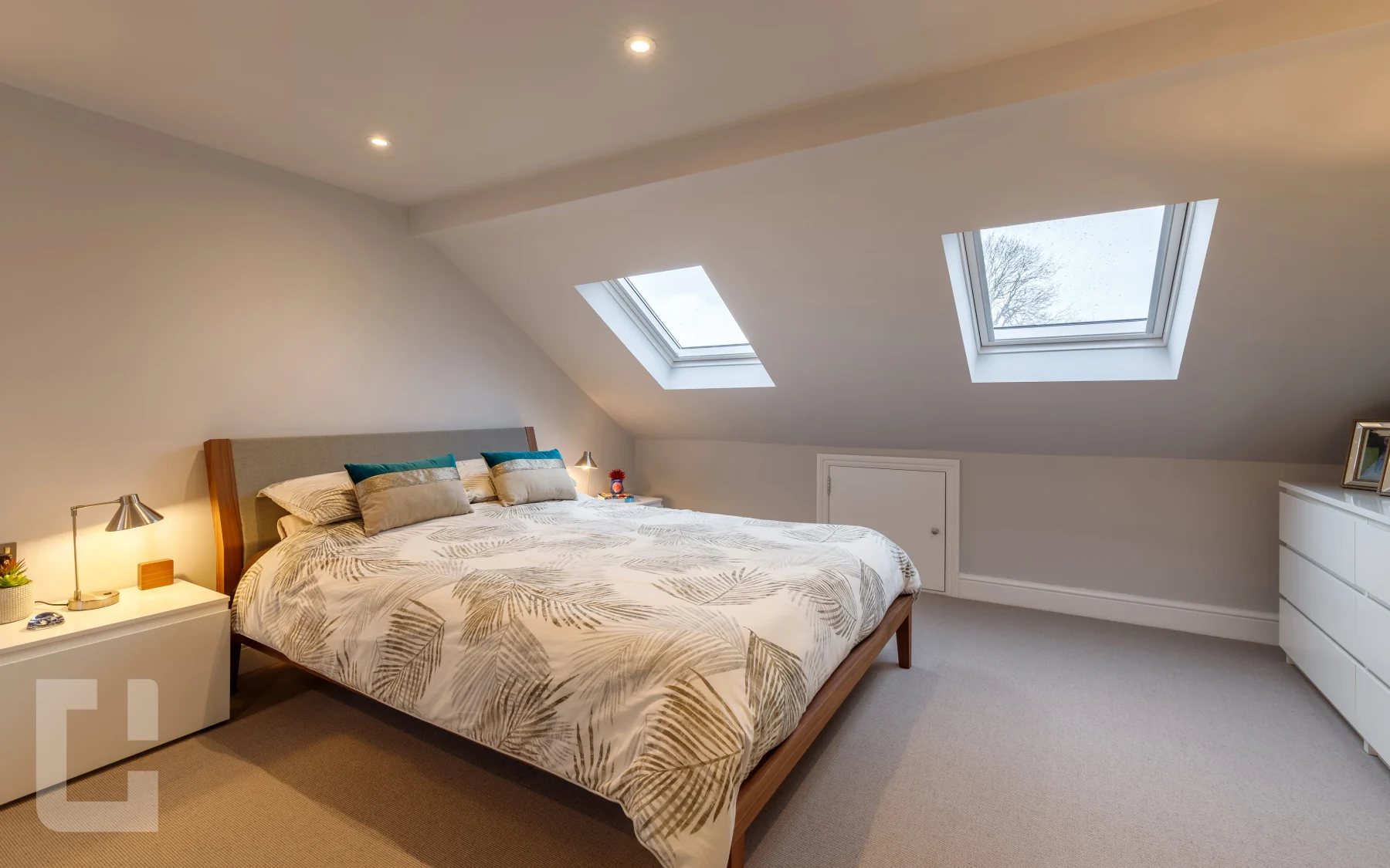 Loft bedroom with two large rooflights in the slope, a knee wall eaves door and a walnut bed