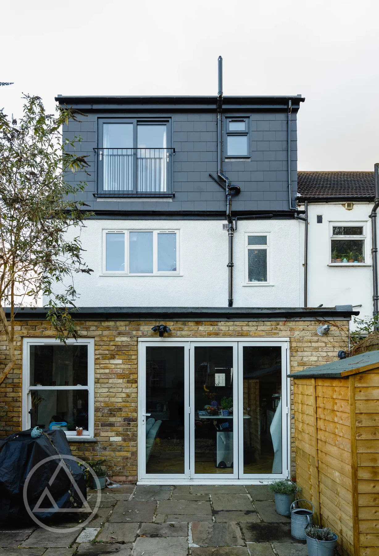 Rear elevation showing a dark-clad loft dormer above a rendered wall and brick rear extension